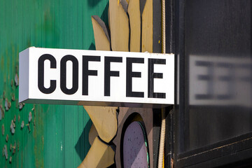 Coffee text sign hanging outside on a building facade of street cafe