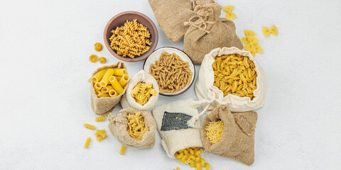 Pasta. Various kinds of uncooked pasta and noodles over light stone background. Traditional Italian