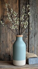 Vase of white budding branches on rustic wood with a gray block