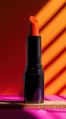 Vibrant orange lipstick tube with dramatic shadows on colorful background