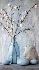 White blossoms in blue vase, smooth gray stones, natural rustic decor