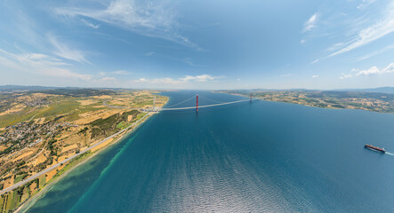 Lapseki, Turkey. Panoramic aerial view of 1915 Canakkale Bridge over Dardanelles Strait with cargo ship passing below on summer day. Aerial view