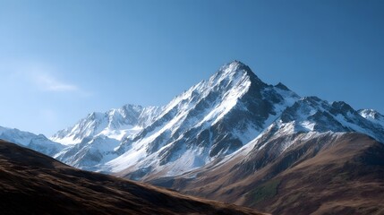 Majestic snow covered mountain peaks dominate a vast landscape under a clear brilliant blue sky