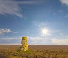 old medieval monument stay among rural ploughland at the sunny day
