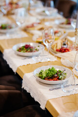 Fancy salad served on a white plate with champagne glass on the side in a restaurant background