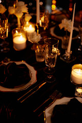 Luxurious setting of dark restaurant tables with candles and fresh flowers
