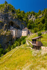 Predjama castle was built within a cave mouth in Slovenian Karst Landscape and it is a popular tourist attraction in an idyllic valley on sunny summer day with fresh flower meadows. Wide angle scenery