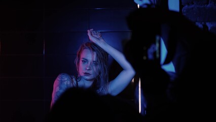 Sexy photo model takes a shower in a swimsuit, poses in front of a switch. Monochrome lighting,...