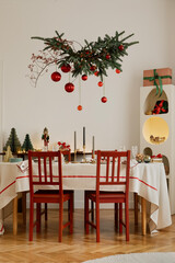 Elegant holiday dining setup with candles, gifts, and red accents. Classic Christmas atmosphere in a modern interior.
