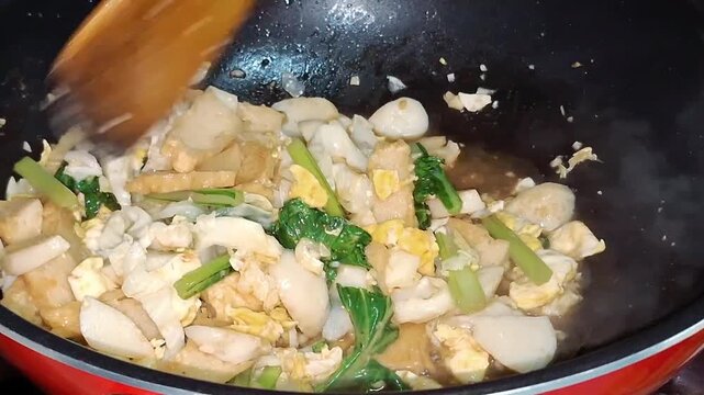 Stir-fry vegetables and fish balls in a hot frying pan.