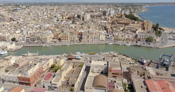 Aerial view of houses and buildings built along a canal. It's Mazaro river, located in the historic center of Mazara del Vallo, in the province of Trapani, Sicily, Italy. It's a beautiful sunny day.
