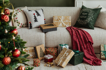 Detail of Christmas decorations and gifts on a beige sofa. Warm red, green, and gold palette creates a festive yet minimalist look.