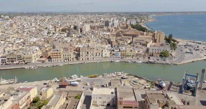 Aerial view of houses and buildings built along a canal. It's Mazaro river, located in the historic center of Mazara del Vallo, in the province of Trapani, Sicily, Italy. It's a beautiful sunny day.
