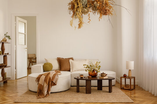 Bright living space with warm autumn colors and natural materials. A floating floral arrangement adds organic charm to the minimalist setting.