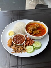 A nasi lemak kari kambing set is a Malaysian meal featuring fragrant rice cooked in coconut milk, served with a rich and aromatic lamb curry.