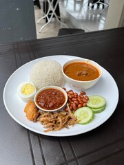 A nasi lemak kari kambing set is a Malaysian meal featuring fragrant rice cooked in coconut milk, served with a rich and aromatic lamb curry.