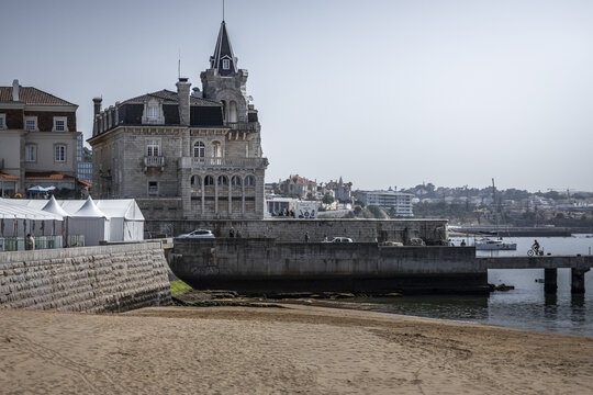 View of the grand, ornate architecture of Museu Condes de Castro Guimar&atilde;es stands majestically by the shore, contrasting with the sandy beach and azure sea, Cascais, Lisbon, Portugal.