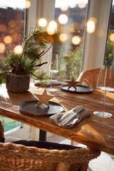 Atmospheric christmas table decoration in a cozy and sunny conservatory with festive bokeh. Vertical gastronomy background.