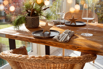 Atmospheric Christmas table decoration in a cozy and sunny conservatory with festive bokeh.