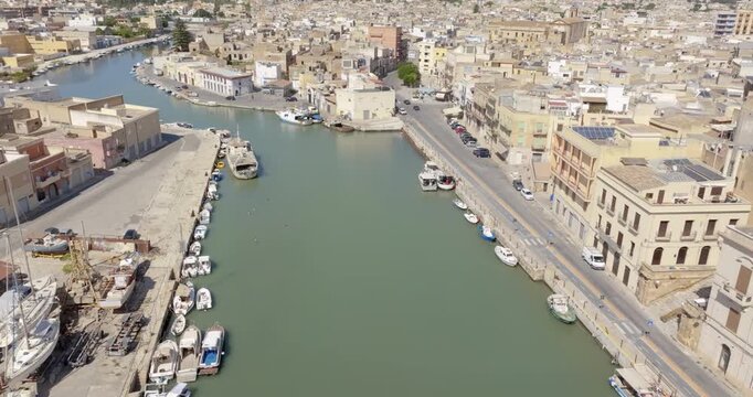 Aerial view of houses and buildings built along a canal. It's Mazaro river, located in the historic center of Mazara del Vallo, in the province of Trapani, Sicily, Italy. It's a beautiful sunny day.