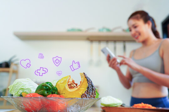 House, fitness and woman in kitchen, smartphone and smile with vegetable, typing and online reading for diet with floating nutritional icons