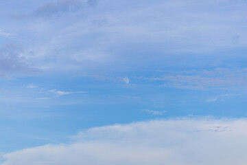 Daytime sky and clouds with moon,Half moon visible in blue sky during daytime,A square photograph showing a bright daytime moon surrounded by soft clouds.