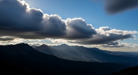 Mountains under dramatic clouds with sun rays piercing through.