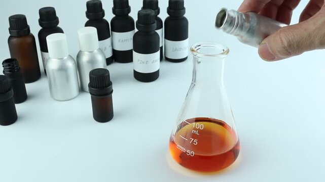 chemical beaker , flask is on white table with blotting paper , fragrance bottle and essential oil bottle are used to blend the nice scent for making perfume and candle by perfumer in the laboratory