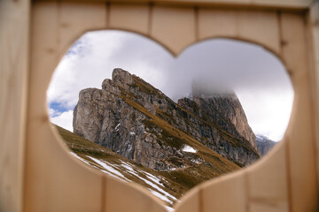 View of Seceda mountain range seen through a heart-shaped opening, Ortisei, Trentino-South Tyrol, Italy.