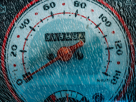 The motorcycle speedometer appears cracked from heat exposure, showing worn plastic texture and highlighting aging vehicle parts in daily use.