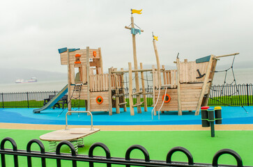 Empty childrens playground with wooden boat, slides and climbing frames