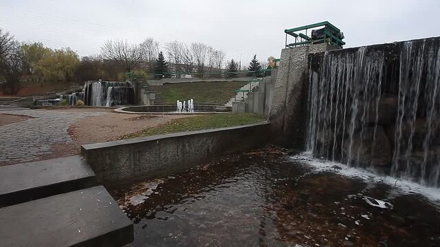 A river waterfall and stone architecture in a city park in spring