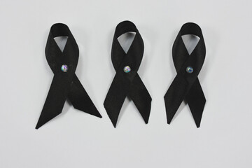 Three black ribbons with iridescent center pins on a white background.