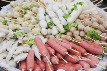 Various sausages and fish balls on skewers ready to cook.