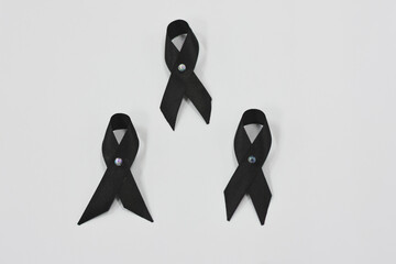 Three black ribbons with iridescent center pins on a white background.