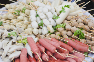 Various sausages and fish balls on skewers ready to cook.