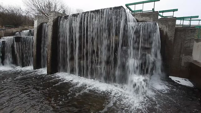 A river waterfall and stone architecture in a city park in spring