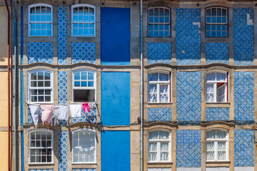Colorful tiled facade with traditional blue azulejos and hanging laundry in Porto city, Portugal. Building facade in old town of Oporto. Travel and tourism in Europe. Portuguese architecture
