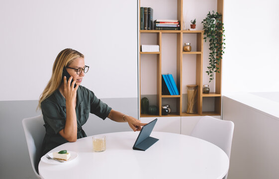 Young woman coordinating on phone while navigating digital tablet during remote work, illustrating active multitasking and connectivity in a mobile-first business environment