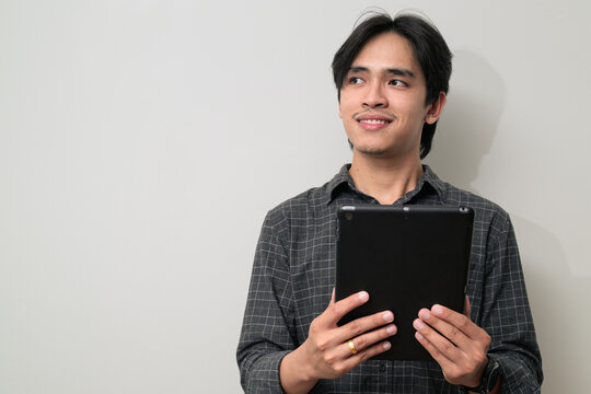 Portrait of handsome Young Asian Thai man using digital tablet computer against white background