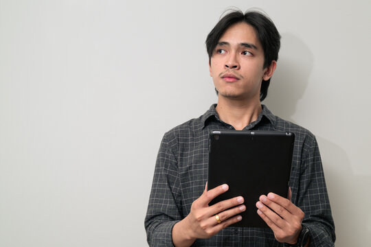 Portrait of handsome Young Asian Thai man using digital tablet computer against white background