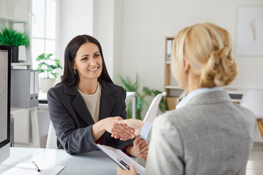 Fototapeta Women corporate colleagues making hand shake gesture, reaching agreement, having negotiations, meeting in office, gathering at briefing, making successful business deal, having success