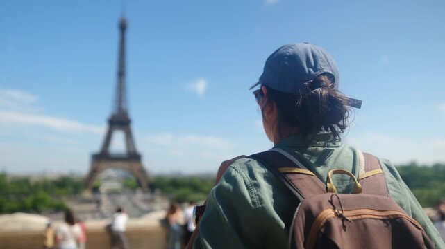 Woman tourist taking a picture of the eiffel tower with a smartphone on a sunny day in paris, enjoying city break travel and sightseeing experience
