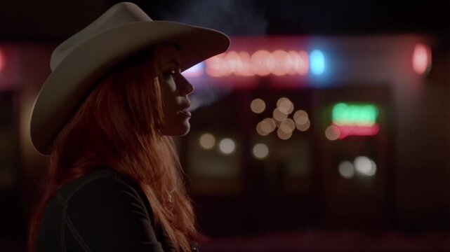 Captivating redhead in cowboy hat enjoys a cigarette outside a neon-lit bar at night, creating a smoky, atmospheric scene with a touch of edgy elegance and vintage charm