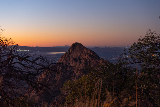 A rock monolith rising over the desert valley at dusk