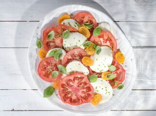 Sliced mozzarella and juicy tomatoes are arranged beautifully on a plate, garnished with fresh basil leaves