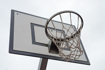 basketball backboard with a hoop and net against a sky