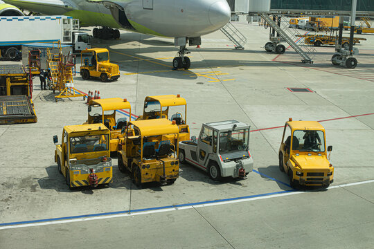 Multiple aircraft pushback tractors and ground support vehicles parked on the tarmac at an airport, ready for aircraft towing and ground operations.