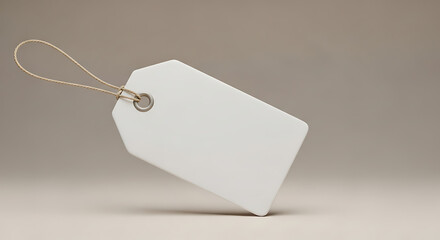 A simple white tag with string attached resting on a neutral surface in a studio setting with soft light