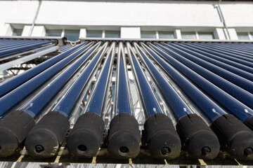 A close-up view of an evacuated tube solar water heater collector. This innovative system, angled towards the sun, represents clean energy, sustainability, and energy-saving technology.